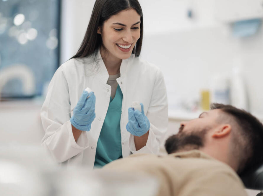 Female dentist showing teeth molds to patient in clinic